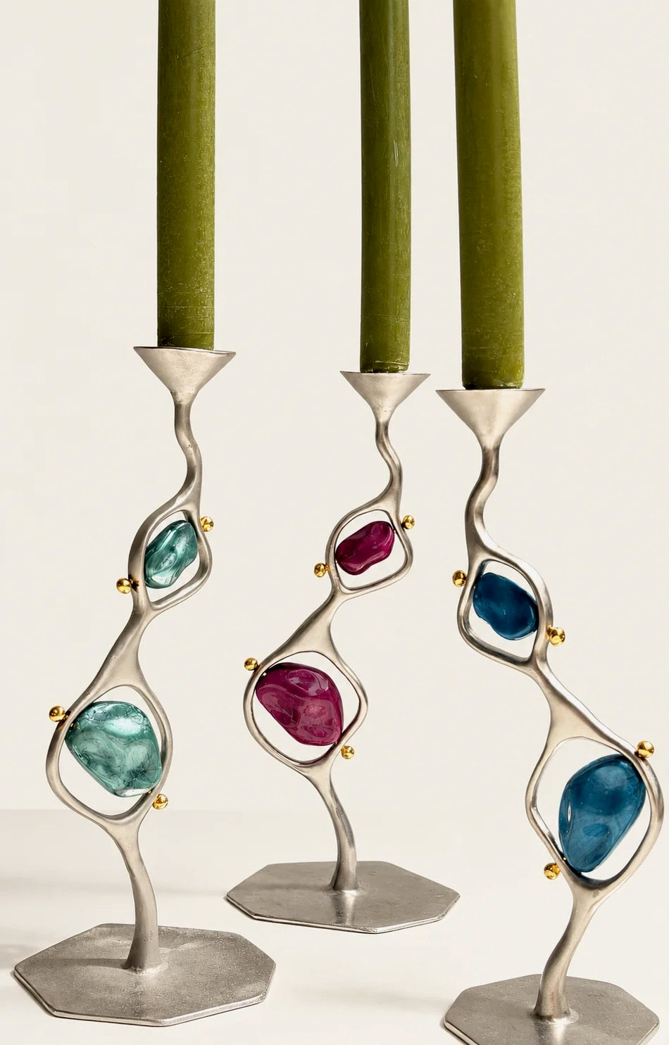 Sculptural silver candlesticks set with colored glass stones and olive taper candles