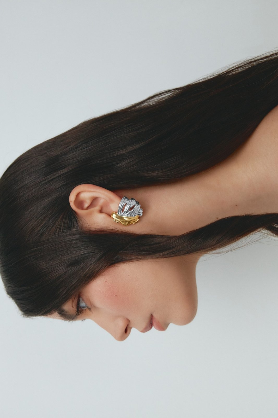 Silver and gold ear cuff worn, hair swept sideways
