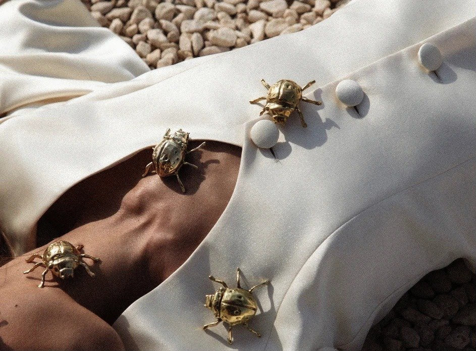 Gold scarab brooches scattered across white satin