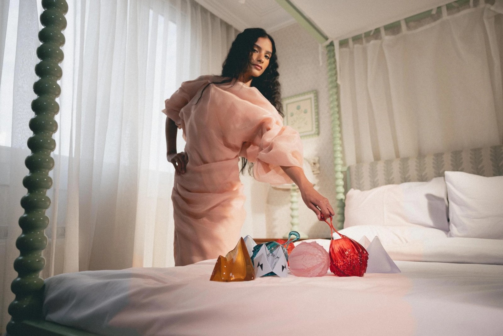 Sculptural glass clutches gathered on a bed
