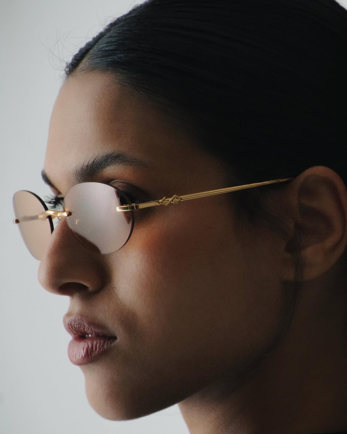 Gold rimless glasses with blush lenses, profile portrait